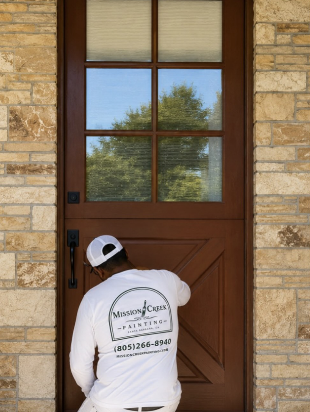 Mission Creek Painting crew member finishing a stained front door in Santa Barbara