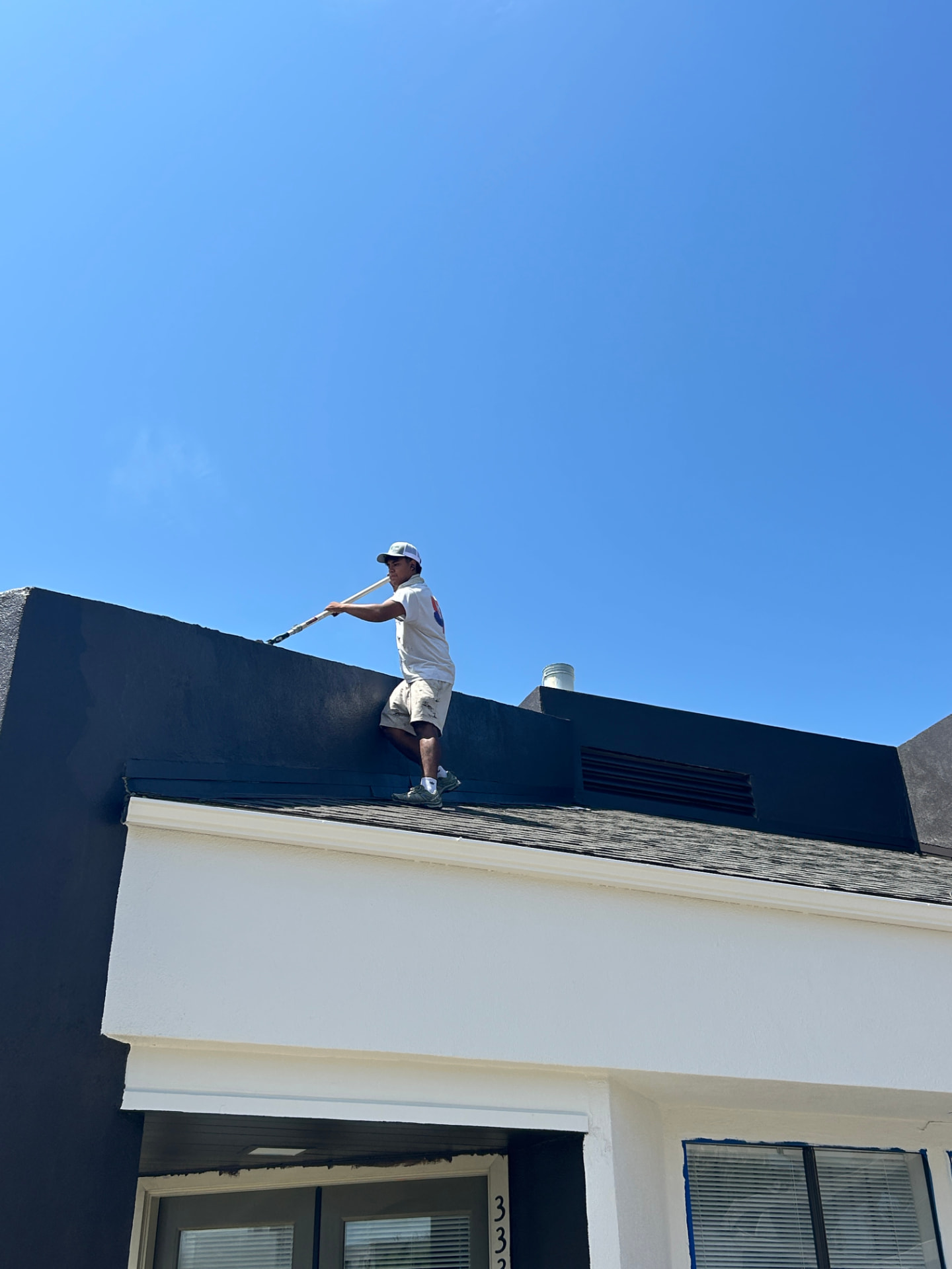 Mission Creek Painting crew member cutting in a roofline parapet on a Santa Barbara exterior repaint