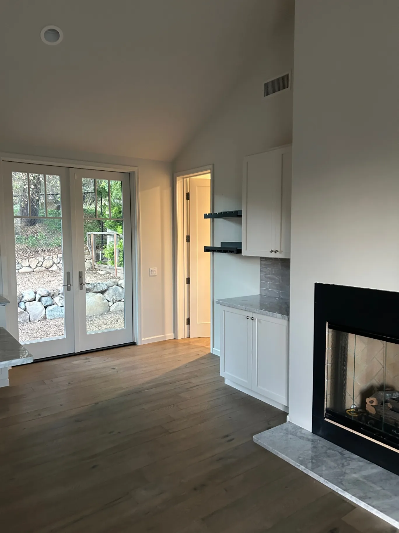 Living area with vaulted ceiling, french doors and built-in shelving