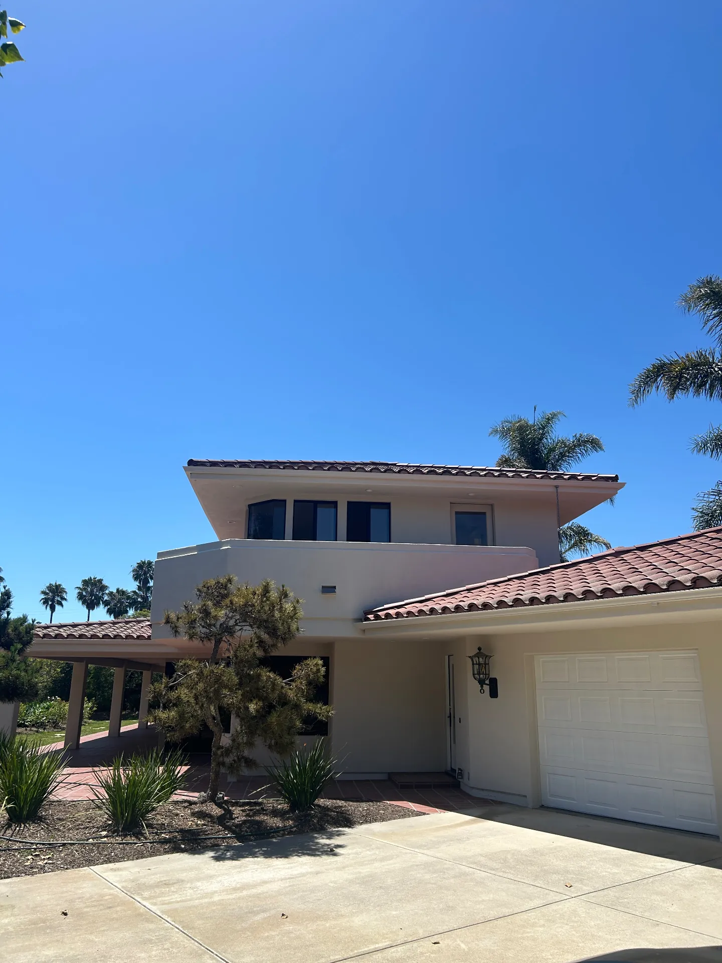 Two-story Spanish Revival home with red tile roof after exterior repaint