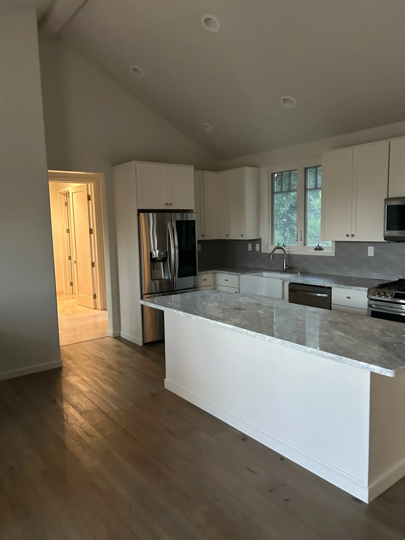 Vaulted kitchen with white shaker cabinets and marble counters