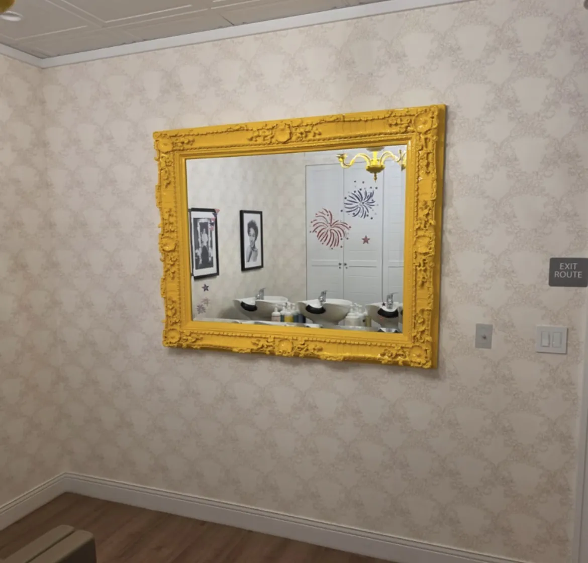 Salon room with patterned wallpaper and gold ornate mirror