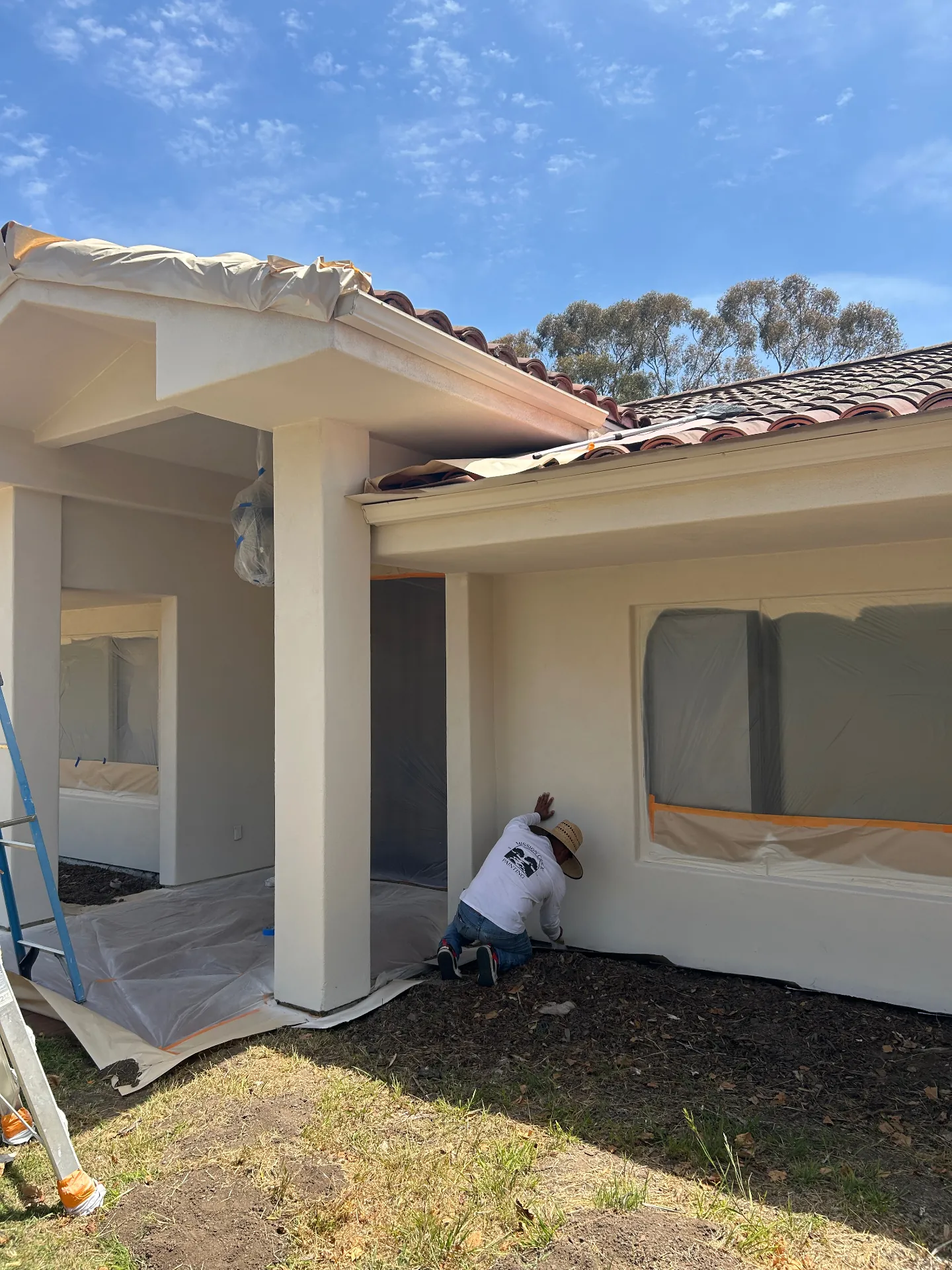 Mission Creek Painting crew member spraying stucco with masked windows