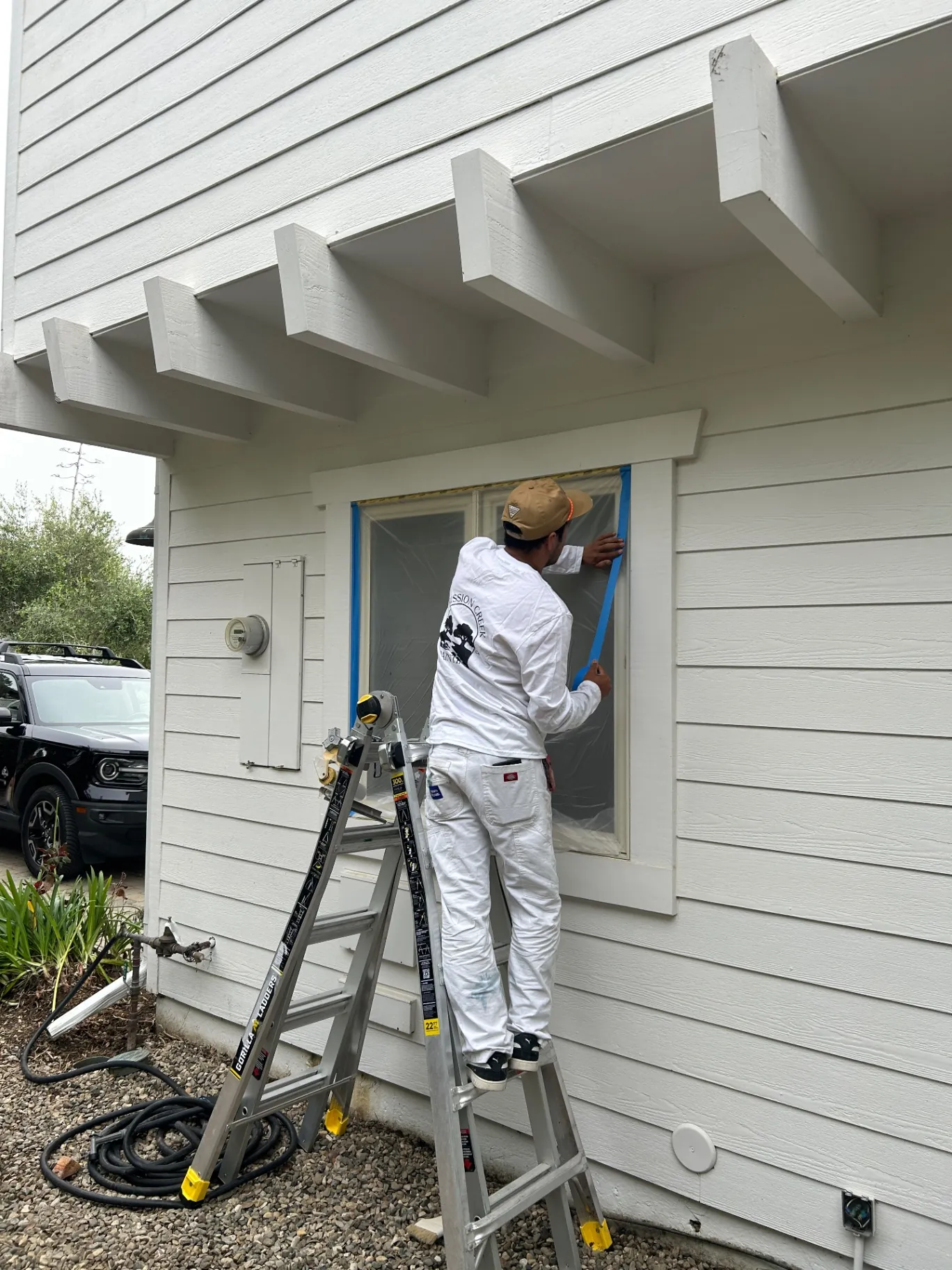 Mission Creek Painting crew member masking a window for spraying