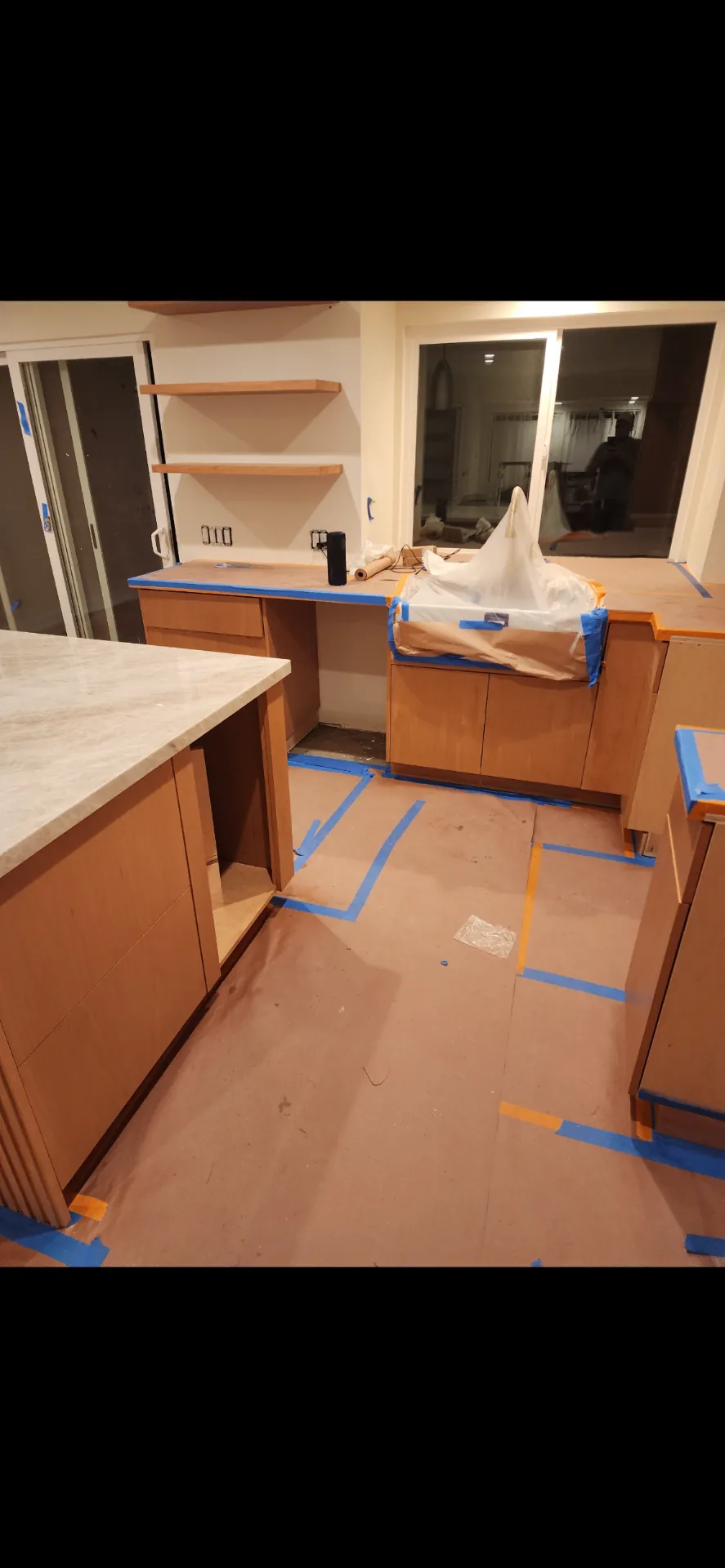 Kitchen cabinets masked and prepped with floor protection before staining