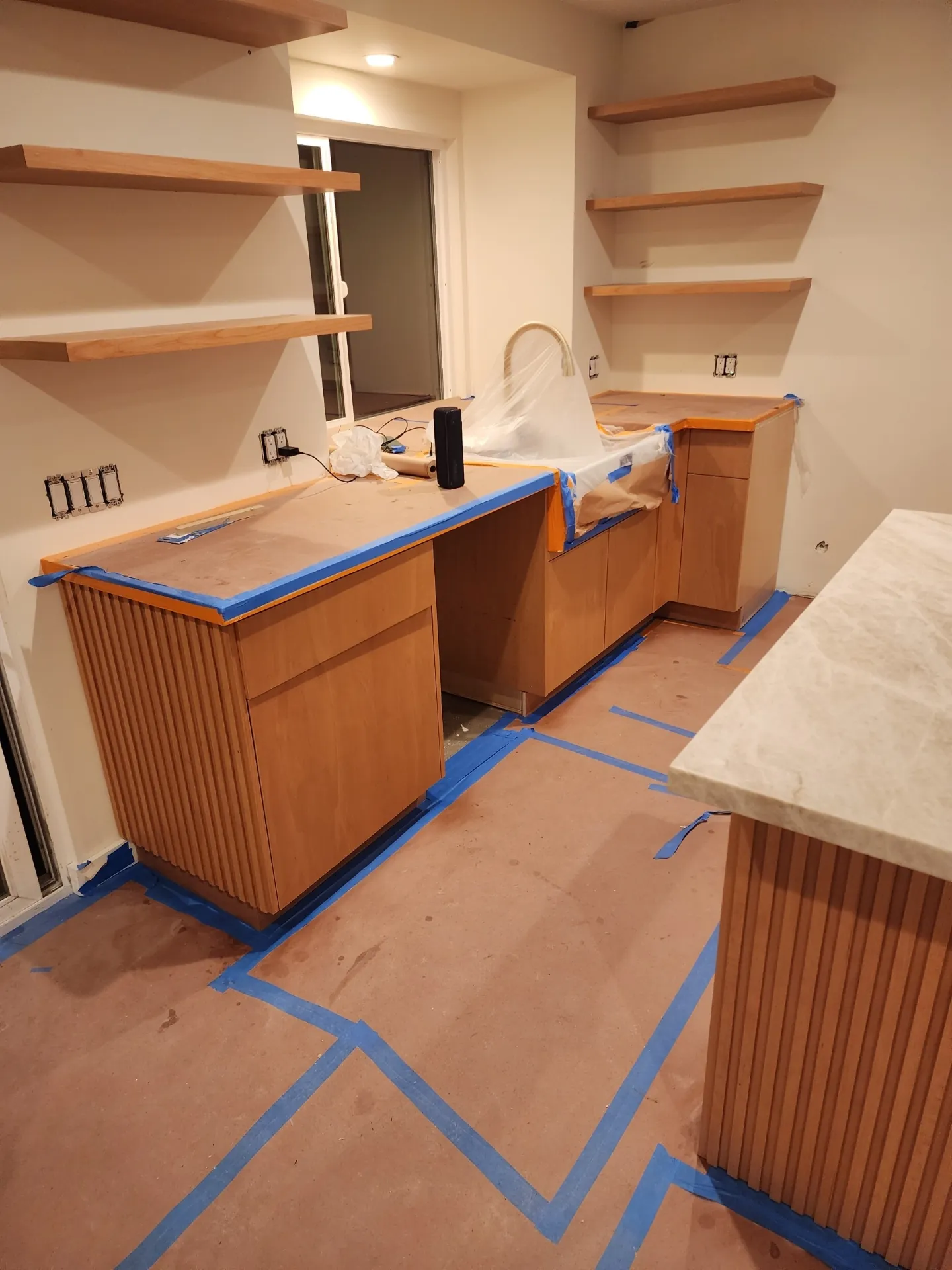 Built-in cabinetry and fluted base masked off with floor papered for stain work